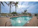 Community pool with lounge chairs and palm trees at 17094 Acapulco Rd # 313, Punta Gorda, FL 33955