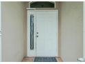 White front door with a sidelight window featuring a diamond pattern at 4401 Boeing Ln, North Port, FL 34287