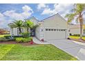 One-story house with a two-car garage, palm trees and landscaping at 5752 Whispering Oaks Dr., North Port, FL 34287