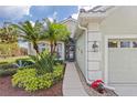 Front entrance of a house with walkway, landscaping, and a two-car garage at 5752 Whispering Oaks Dr., North Port, FL 34287