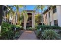 Brick walkway leads to a condo building with lush landscaping and palm trees at 23465 Harborview Rd # 1006, Punta Gorda, FL 33980