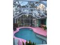 Kidney-shaped pool with pink deck and screened enclosure at 1281 Nebraska Ln, North Port, FL 34286