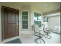 Covered front porch with two chairs and a view of the front yard at 6104 Plamendon Ave, North Port, FL 34291