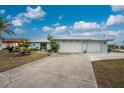 Two-story home with light teal exterior, two-car garage, and mature landscaping at 840 Via Tunis, Punta Gorda, FL 33950