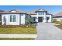 Two-story home with a gray tile roof, white walls, and a paver driveway at 10628 Nicklaus Ct, Englewood, FL 34223