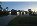 Night view of a white house with a dark garage door at 12547 Trinity Ave, Port Charlotte, FL 33953