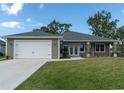 One-story house with gray siding, white garage door, and a landscaped lawn at 16305 Branco Dr, Punta Gorda, FL 33955