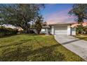 White single-story house with attached garage, viewed at dusk at 21190 Midway Blvd, Port Charlotte, FL 33952