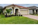 Tan house with tile roof, two-car garage, and manicured lawn at 4269 River Bank Way, Port Charlotte, FL 33980