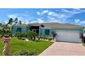 House exterior with landscaped lawn, paver driveway, and white garage door at 8117 Thruso Rd, Port Charlotte, FL 33981