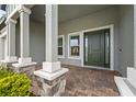 Front porch with stone columns and brick flooring at 19916 Bridgetown Loop, Venice, FL 34293