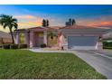 Evening view of a pink one-story home with a two-car garage at 632 Balsam Apple Dr, Venice, FL 34293