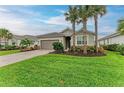 Single story house with a two-car garage, well-manicured lawn, and palm trees at 15169 Spanish Point Dr, Port Charlotte, FL 33981