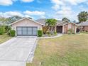 Single-story home with attached garage, landscaping, and a large front yard at 18305 Wolbrette Cir, Port Charlotte, FL 33948