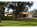 Charming single-story home with a screened-in porch, attached garage, and well-maintained lawn nestled among mature trees at 21217 Knollwood Ave, Port Charlotte, FL 33952