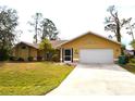 Bright yellow house with a two-car garage and well-manicured lawn at 21217 Knollwood Ave, Port Charlotte, FL 33952