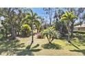 Lush landscaping with a variety of palm trees and flowering shrubs creates a tropical oasis in the front yard at 21217 Knollwood Ave, Port Charlotte, FL 33952