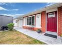 Red front door and brick facade with a small bench at 4657 Nele St, North Port, FL 34287