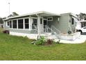 Side view of a single-wide mobile home showing a large covered porch and a small garden at 5448 Joy Ct, North Port, FL 34287