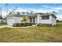 White house with a two-car garage, palm trees, and manicured lawn at 99 Sundiet St, Port Charlotte, FL 33954