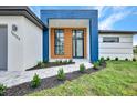 Modern home with a blue and white exterior, a wooden door, and landscaped walkway at 15133 Amsterdam, Port Charlotte, FL 33981