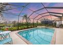 Screened-in pool and spa overlooking lush landscaping and a picturesque lake view at 25187 Keygrass Ct, Punta Gorda, FL 33955