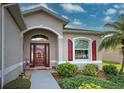 Front entrance with red door, arched windows, and landscaping at 1347 Hedgewood Cir, North Port, FL 34288