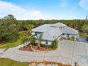 Expansive aerial view of a home with a large driveway surrounded by lush greenery and mature landscaping at 700 N River Rd, Venice, FL 34293