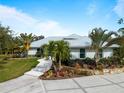 Landscaped grounds surround this single-story home with metal roof and walkway at 700 N River Rd, Venice, FL 34293