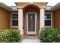 Front entrance with columns, decorative screen door, and lush landscaping at 26191 Copiapo Cir, Punta Gorda, FL 33983