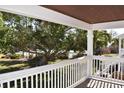 Wood balcony with white railings overlooking a green lawn with a large banyan tree and community pool at 108 Pompano Se Dr # D, St Petersburg, FL 33705