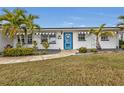 Front view of a charming home with a blue door, striped awnings and landscaping at 226 Spring Lake Nw Blvd, Port Charlotte, FL 33952