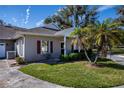 Tan house with red shutters and a two-car garage, surrounded by lush landscaping at 1447 Red Oak Ln, Port Charlotte, FL 33948