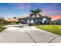 Gray house with palm trees and a large driveway at sunset at 18138 Eau Gallie Cir, Port Charlotte, FL 33948