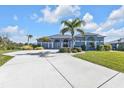 Front view of a single-story house with a large driveway and palm trees at 18138 Eau Gallie Cir, Port Charlotte, FL 33948