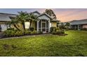 Evening view of a yellow house with a screened porch and lush landscaping at 2110 Royal Tern Cir, Punta Gorda, FL 33983