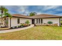 House exterior with stone accents and a nicely manicured lawn at 245 Brighton Ct, Englewood, FL 34223