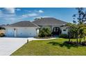 Three-car garage, light beige exterior, and lush landscaping at 269 Mariner Ln, Rotonda West, FL 33947