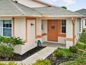 Inviting front entrance with a peach-colored door, walkway, and well-maintained landscaping at 483 Winwood Ct, Port Charlotte, FL 33954