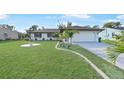 White house with gray roof, palm trees, and a spacious driveway at 813 Thornton Nw Ave, Port Charlotte, FL 33948