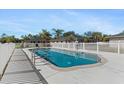 Community pool with surrounding fence and lounge chairs at 24540 Harborview Rd # E4, Port Charlotte, FL 33980