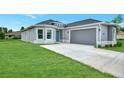 Newly built home with gray siding, attached garage, and grassy yard at 4629 Enid Ln, North Port, FL 34288