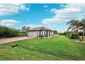 One story house with gray roof, white garage door, and grassy yard at 102 Linda Lee Dr, Rotonda West, FL 33947