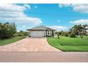 Single story home with gray roof and a brick driveway at 102 Linda Lee Dr, Rotonda West, FL 33947