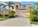 Two-story house with a peach-colored facade, two-car garage, and lush landscaping at 1811 Scarlett Ave, North Port, FL 34289