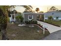 Charming exterior showcasing the manufactured home's carport and meticulously landscaped yard with palm trees at 6671 Keystone Ct, North Port, FL 34287