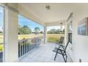 Covered front porch with tiled floor and two chairs, overlooking a yard at 17521 Pomegrante Way, Punta Gorda, FL 33955