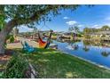 Waterfront backyard featuring a hammock, canal view, blue chairs, and tropical landscaping at 18390 Burkholder Cir, Port Charlotte, FL 33948