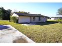 Side view of the house with a concrete driveway and a green lawn at 4200 Kilpatrick St, Port Charlotte, FL 33948