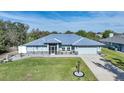 Single-story home with metal roof, light blue siding, and landscaped lawn at 7435 Snow Dr, Englewood, FL 34224